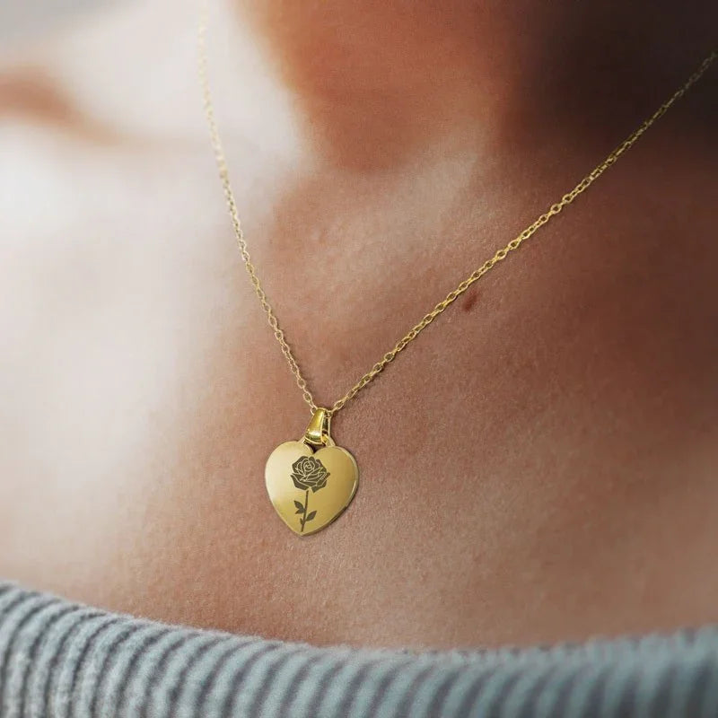 Colgante dorado en forma de corazón con rosa grabada, ideal para regalo divertido y especial.